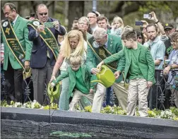  ?? ?? Right: Alicia Coleman and Lawrence “Bubba” Edgerly and kids Joe (left) and Chase Neagle pour green water into Forsyth fountain during the event that kicks off parade festivitie­s.