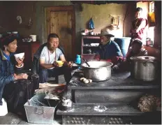  ??  ?? A woman and her family having a breakfast consisting of yak butter tea and tsampa in their kitchen in Zhaba.