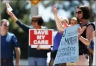  ?? THE ASSOCIATED PRESS ?? Cindy Fandhu, front right, holds her 18-month-old daughter, Jocelyn, as they wave to supporters Thursday during a protest in Aurora, Colo., outside the office of U.S. Rep. Mike Coffman, R-Colo., over the health care overhaul bill up for a vote in the...