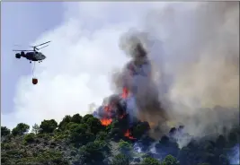  ?? GREGORIO MARRERO — THE ASSOCIATED PRESS ?? A helicopter drops water as a wildfire rages near a residentia­l area in Malaga, Spain, on Saturday. Wildfires continue to spread across Spain.