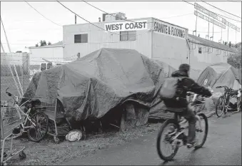  ?? [TED S. WARREN/ ASSOCIATED PRESS FILE PHOTO] ?? A person cycles past tents set up along a pathway, Sept. 19, 2017, in Portland, Ore.