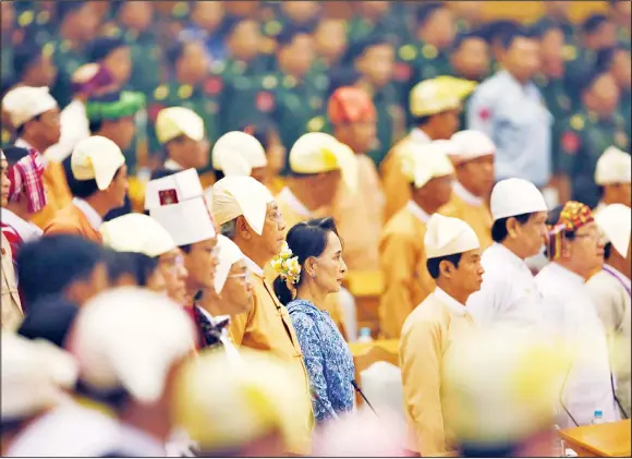 ??  ?? Aung San Suu Kyi (center in blue), and Htin Kyaw (next to her), newly elected president of Myanmar, stand during a ceremony to take oaths in parliament in Naypyitaw, Myanmar, on March 30. SuuKyi’s aide Htin Kyaw took oath on Friday as a new civilian government takes over Myanmar, after 54 years of rule by the junta or its proxy. (AP)