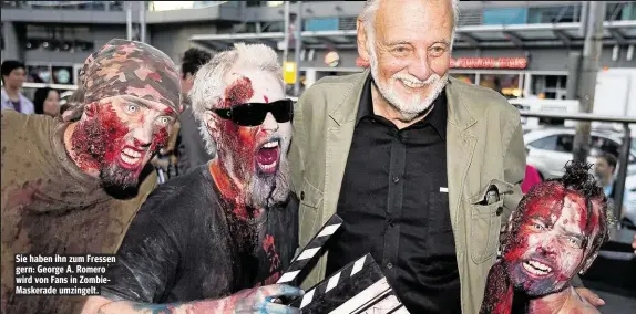  ??  ?? Sie haben ihn zum Fressen gern: George A. Romero wird von Fans in ZombieMask­erade umzingelt.