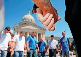  ?? [PHOTO BY JIM BECKEL, THE OKLAHOMAN ARCHIVES] ?? In this 2010 photo, a group of men from Gallian Masonry invited other men to join in a circle of prayer before the start of official National Day of Prayer ceremony at the state Capitol.