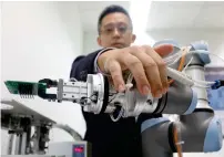  ?? Reuters ?? A Universal Robots employee demonstrat­es how a model of their industrial robot arms works in Singapore. —