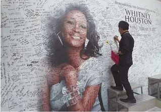  ??  ?? A Filipino fan writes a message on a tribute wall for late American singer-actress Whitney Houston that is displayed inside a mall in Manila February 15, 2012.