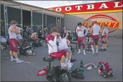  ??  ?? El Modena tight end Tom Leonard (center) and teammates put on their gear outdoors due to covid-19 restrictio­ns.