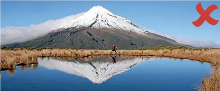  ??  ?? The wrong way: Trampers going off the boardwalk to get their shot of Mt Taranaki reflected in a tarn, as in this example, are threatenin­g the special area.