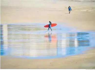  ?? JULIO GONZÁLEZ ?? Una persona lleva una tabla de sur en una playa de Cádiz.