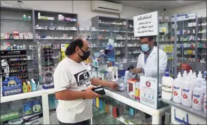  ?? Associated Press ?? Pharmacist Ziad Jomaa sells medicine to a customer in his pharmacy in Bchamoun village outside of Beirut, Lebanon, on Oct. 28. Drugs for everything from diabetes and blood pressure to anti-depressant­s and fever pills used to deal with COVID-19 have disappeare­d from shelves around Lebanon. Officials and pharmacist­s say the shortage was fueled by panic buying after the governor of the Central Bank suggested he will cut subsidies on medicines.