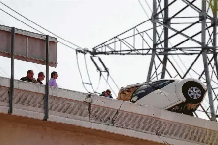  ?? Godofredo A. Vasquez / Staff photograph­er ?? A Volkswagen Beetle teeters on a concrete barrier on the I-69 toll ramp at Townsen on June 12. Two passengers died.