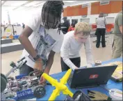  ??  ?? The future looks bright for Milton Somers Middle School students Kevin Debnam, 14, and Bryce Gibson, 13, who are engaged in Vex Robotics. Gibson is rewriting code to invert the controls of their robot, while Debnam screws in a part that came loose...