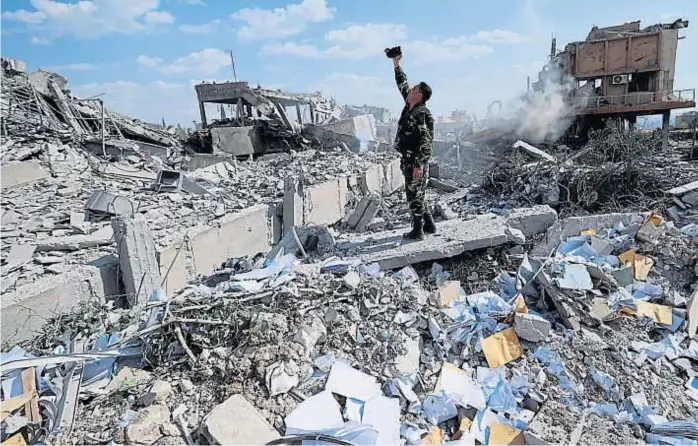  ?? (AP) ?? Ruinas. Un soldado sirio filma el resultado del ataque del viernes contra un centro de desarrollo científico, cerca de Damasco. Fue uno de los blancos de EE.UU., de Francia y del Reino Unido.