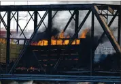 ?? ROSS D. FRANKLIN — THE ASSOCIATED PRESS ?? A derailed freight train burns on a bridge spanning Tempe Town Lake on Wednesday in Tempe, Arizona.