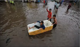  ?? AP Photo/Ajit Solanki ?? Flooding: Indian children play in floodwater­s after heavy rainfall in Ahmadabad, India, Friday. India receives its annual rainfall from June-October.