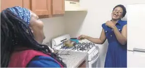  ?? KIM HAIRSTON/BALTIMORE SUN ?? Anifa Sanza shares a laugh with translator Juliah Kangara as she cooks dinner.