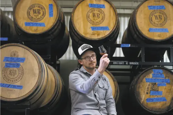  ?? Paul Chinn / The Chronicle ?? Cofounder Earl Brown inspects whiskey aging in 200liter barrels at Wright & Brown Distilling Co. in Oakland. He uses local grains, maltings and barrels.