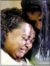  ??  ?? Survivor Tia Coleman, who lost nine family members, is comforted by her sister after speaking with the media.