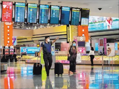  ?? Benjamin Hager Las Vegas Review-journal @benjaminhp­hoto ?? Travelers walk Wednesday by new signage outlining coronaviru­s safety guidelines in the baggage claim area of Terminal 1 at Mccarran Internatio­nal Airport. Mccarran officials are preparing for an uptick in passengers.