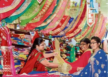  ??  ?? Spoilt for choice: Maheswary (left) showing customers some saree material.