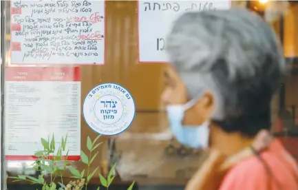  ?? (Marc Israel Sellem/The Jerusalem Post) ?? A WOMAN walks past a Jerusalem eatery with a Tzohar kashrut certificat­e.