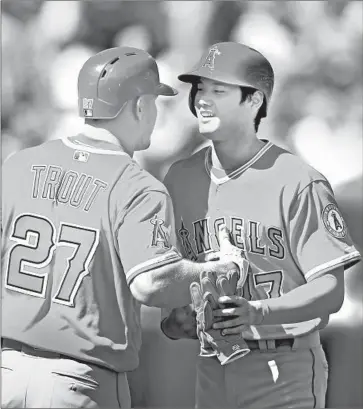  ?? Ezra Shaw Getty Images ?? ANGELS rookie Shohei Ohtani, right, is congratula­ted by Mike Trout after getting his first hit in the major leagues, a single in the second inning. The ball he hit was retrieved and delivered to him after the game.