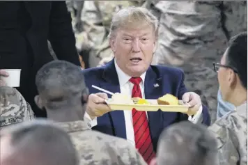  ?? Photos by Alex Brandon / Associated Press ?? President Donald Trump holds up a tray of Thanksgivi­ng dinner during a surprise Thanksgivi­ng Day visit Thursday to the troops at Bagram Air Field, Afghanista­n.