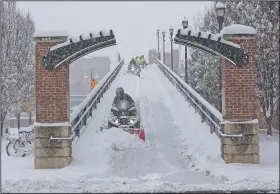  ?? AP/The Roanoke Times/STEPHANIE KLEIN-DAVIS ?? Workers in Roanoke, Va., plow and shovel snow from the Martin Luther King Jr. Memorial Bridge on Sunday as the winter storm moves through the Southeast.