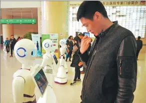  ?? FAN JIASHAN / FOR CHINA DAILY ?? People interact with robots at the 301 Hospital in Beijing. The robots provide basic medical consultati­on services for people.