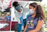  ?? BEN GRAY FOR THE ATLANTA JOURNAL-CONSTITUTI­ON ?? Ashanti Booker, a registered nurse with the DeKalb County Board of Health, gives a COVID-19 vaccinatio­n to Raya High, 13, at a mobile clinic at Decatur High School on Monday.