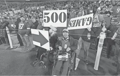  ?? MARK HOFFMAN / MILWAUKEE JOURNAL SENTINEL ?? Brian Gushue (center) was able to get on the field before the Green Bay Packers game against the Detroit Lions Monday at Lambeau Field. His friends made signs to celebrate that this was Brian’s 500th NFL game, despite the challenges of having cerebral...