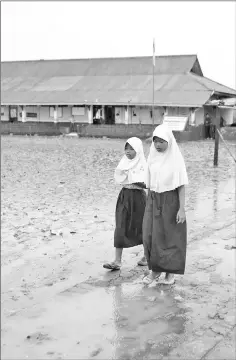  ??  ?? Students walk in the yard of the Pantai Bahagia Elementary School, before tide comes in, in Bekasi, West Java province.