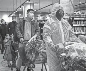  ?? GETTY IMAGES ?? Residents wear protective masks as they line up in a supermarke­t Feb. 12 in Wuhan, China. The country shut down flights, trains and public transport after the outbreak of the novel coronaviru­s that causes COVID-19.