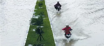  ??  ?? PEOPLE RIDE motorcycle­s along a flooded road in Hue yesterday.