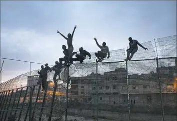  ?? Santi Palacios/Associated Press ?? Sub-Saharan migrants climb over a fence that divides Morocco and the Spanish enclave of Melilla in 2014.