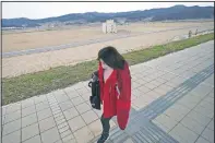  ??  ?? A woman walks past the ruin of a building destroyed by the 2011 tsunami in Rikuzentak­ata. In Rikuzentak­ata more than 1,700 people died in the disaster.