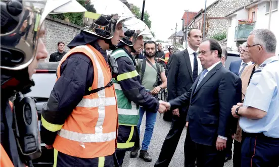  ?? — Reuters ?? Hollande shakes hands with firemen as he arrives after a hostage-taking at the church in Saint-Etienne-du-Rouvray, France.