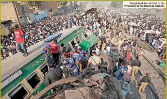  ??  ?? People look for victims in the wreckage of the trains in Karachi.
