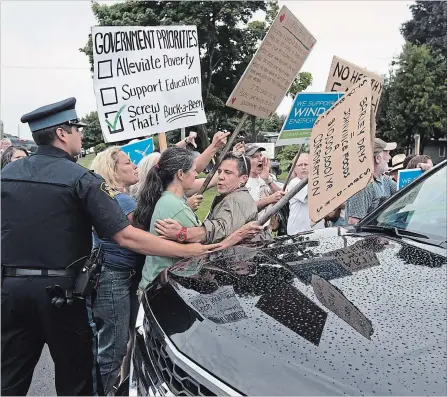  ?? LARS HAGBERG
THE CANADIAN PRESS ?? Police move protesters as Ontario Premier Doug Ford’s car leaves the buck-a-beer plan announceme­nt at Barley Days Brewery in Picton, Ont.