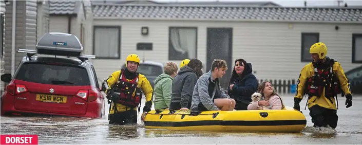  ?? ?? Evacuation: Firefighte­rs use an inflatable boat to rescue a family and their pet dog from flooded holiday chalets at Freshwater Beach in Burton Bradstock