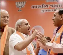  ?? PTI ?? Chief Minister Vijay Rupani offers sweets to Deputy CM Nitin Patel as Arun Jaitley (left) looks on in Gandhinaga­r on Friday. —