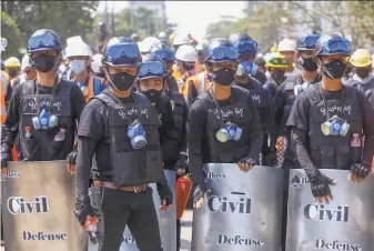  ?? Associated Press ?? Anticoup protesters watch from front lines in Yangon, Myanmar. Despite the increasing­ly violent tactics of security forces, protests continued in cities and towns across the country.