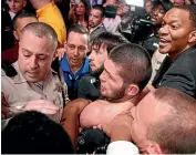  ?? AP ?? Khabib Nurmagomed­ov, centre, is held back after leaping out of the cage and attacking Conor McGregor’s trainer in Las Vegas.