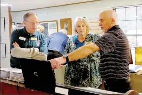  ?? Lynn Atkins/The Weekly Vista ?? During the annual open house, Melissa Kendus shows members of the Bella Vista History Museum’s board of directors, John Flynn (left) and Steve Morrow, a slide show about the Wonderland Cave. She and her husband, Nick Kendus, helped clean out the cave over the last several years.