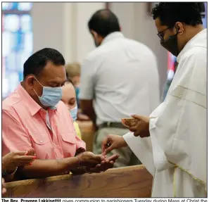  ?? (AP/Eric Gay) ?? The Rev. Praveen Lakkisetti­t gives communion to parishione­rs Tuesday during Mass at Christ the King Catholic Church in San Antonio, where parishes have reopened after weeks of being shut down. Texas officials are defending their statistics on coronaviru­s testing in the face of some health experts’ skepticism. More photos at arkansason­line.com/520virus/.