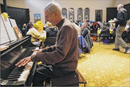  ?? Photos by Paul Buckowski / times union ?? Volunteer Wally Jones of Selkirk plays the piano to entertain those taking part in the equinox thanksgivi­ng day community dinner on thursday at first Presbyteri­an Church in Albany. At left, volunteers serve attendees. many of the volunteers have been prepping and cooking the food since Sunday.