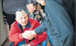  ?? KYLE TELECHAN/POST-TRIBUNE ?? Pearl Harbor survivor Jim DeWitt shakes hands with the Rev. Mike Maginot during the Pearl Harbor Remembranc­e Day Memorial Service in Highland on Saturday,