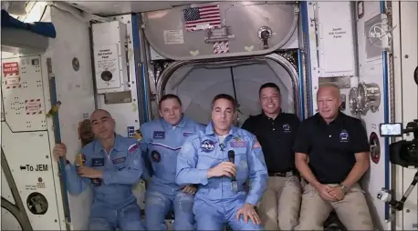  ?? NASA VIA AP ?? This photo provided by NASA shows Bob Behnken and Doug Hurley, far right, joining the crew at the Internatio­nal Space Station, after the SpaceX Dragon capsule pulled up to the station and docked Sunday.