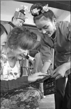  ??  ?? Left: Natalie Gibson gets a close look at Miao embroidery during her trip to Guizhou. Right: Gibson is drawn by the batik pieces on display in a local museum.