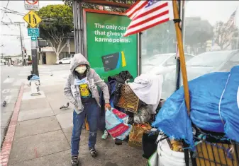  ?? Photos by Gabrielle Lurie / The Chronicle ?? A homeless woman who did not wish to give her name takes precaution­s as she prepares her belongings in San Francisco. The city may shelter people at such sites as churches and schools.